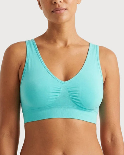 A woman wearing a light aqua Original Ahh Bra® against a light gray studio background.