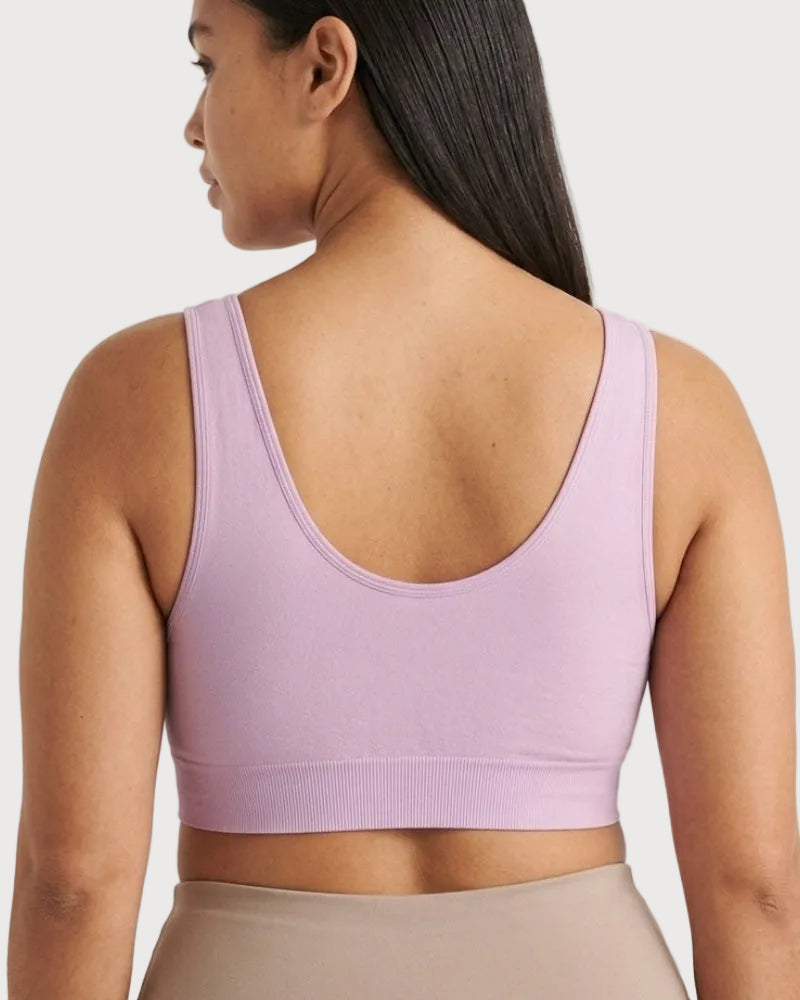 A woman shown from the back wearing a light purple Original Ahh Bra®, paired with beige bottoms, against a light gray studio background.