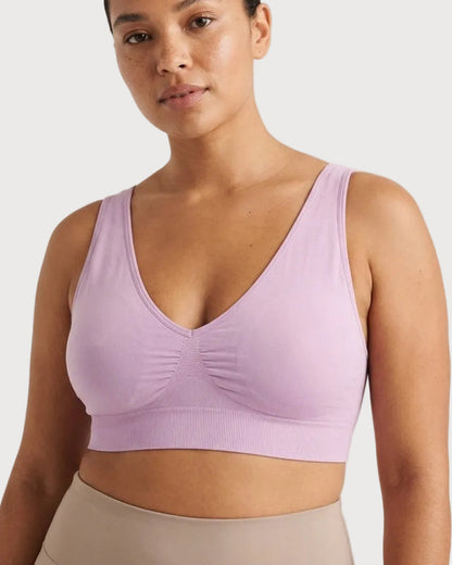 A woman wearing a light lavender Original Ahh Bra®, paired with beige leggings, against a plain light background.