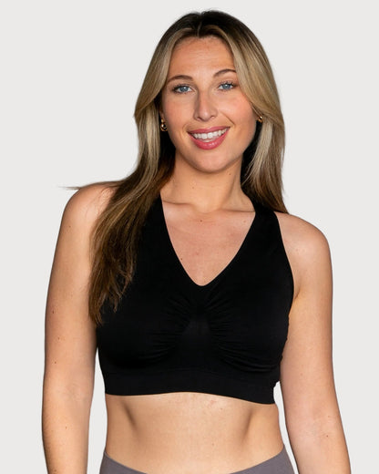 A woman wearing a black Seamless Racerback Ahh Bra, shown against a solid light gray background.